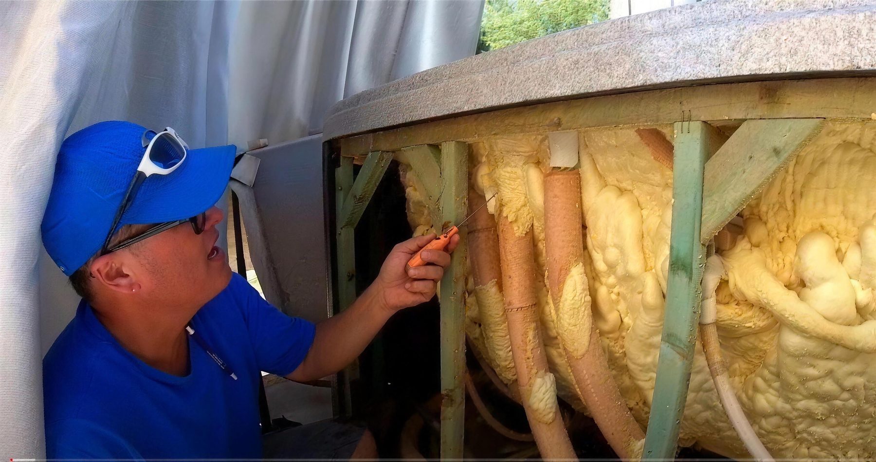 Scott Cebulski in his blue cap working inside a hot tub cabinet
